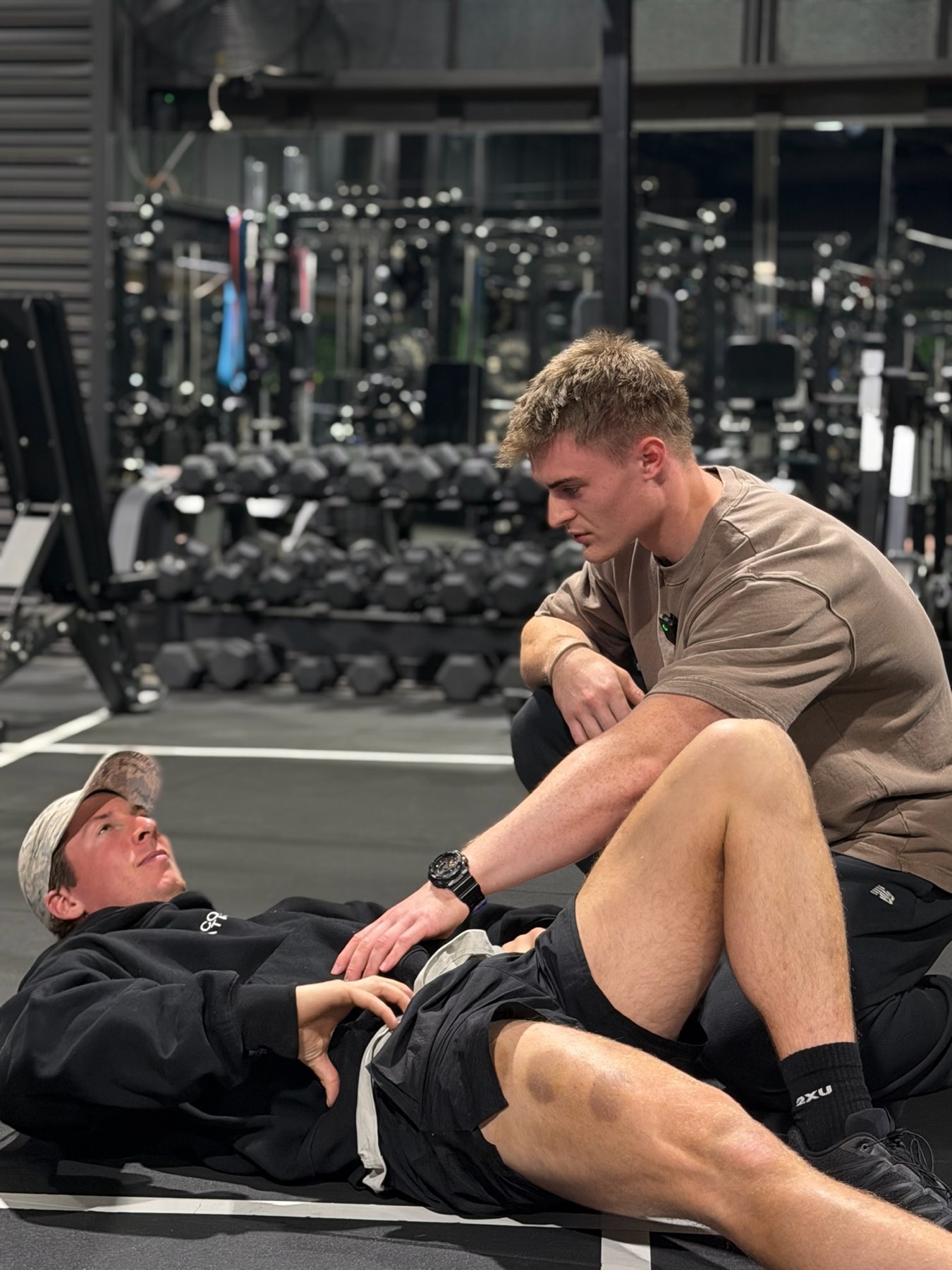 Remy assessing a client's hip on the gym floor